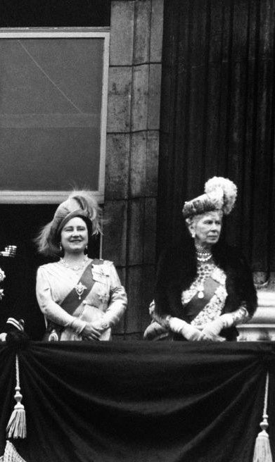 the Queen Mother and Queen Mary wearing royal garb and standing