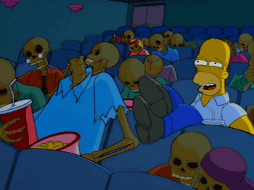 Homer laughs in a movie theater filled with skeletons