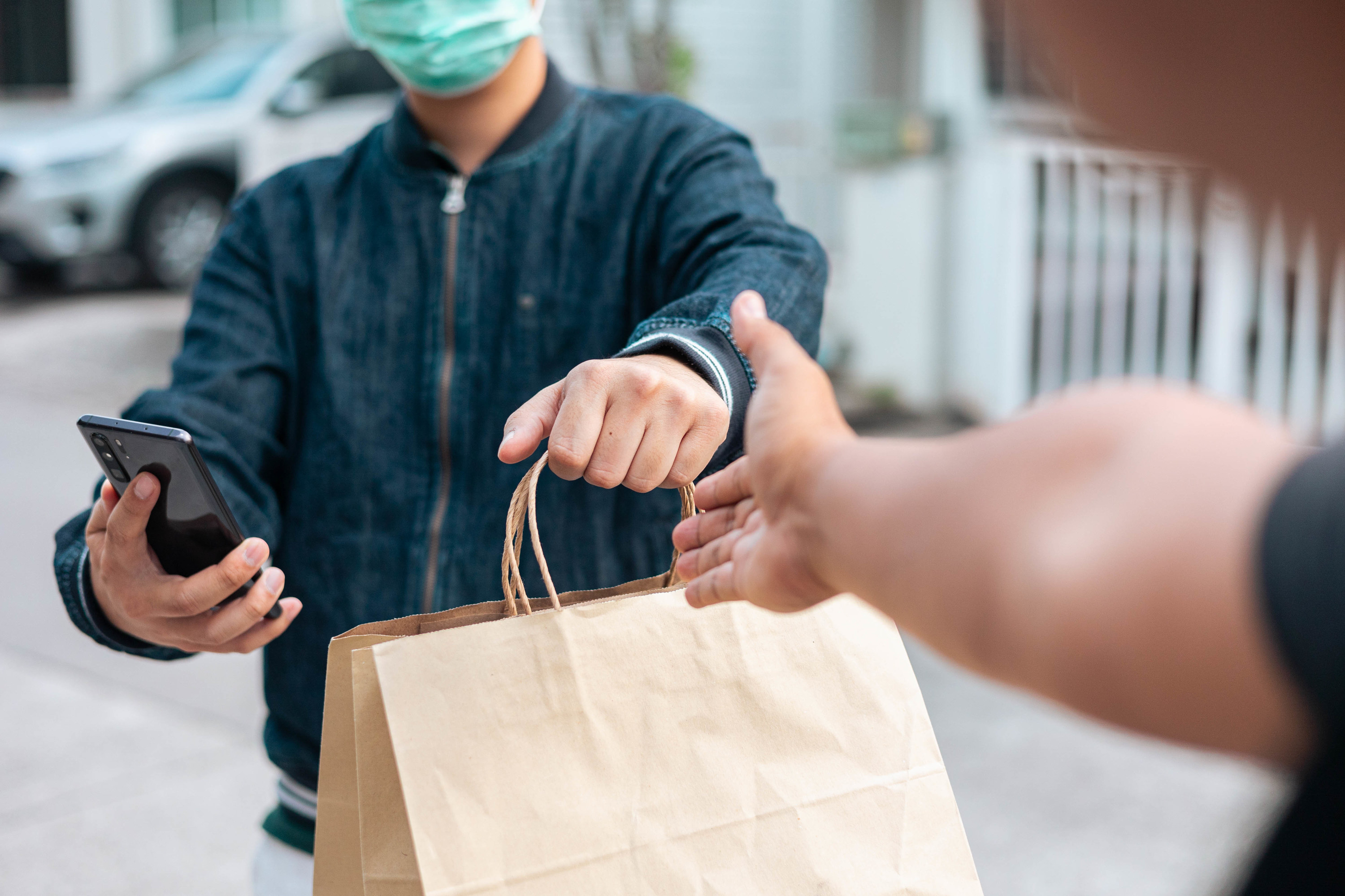 Person handing over a shopping bag to someone else and taking a picture of it