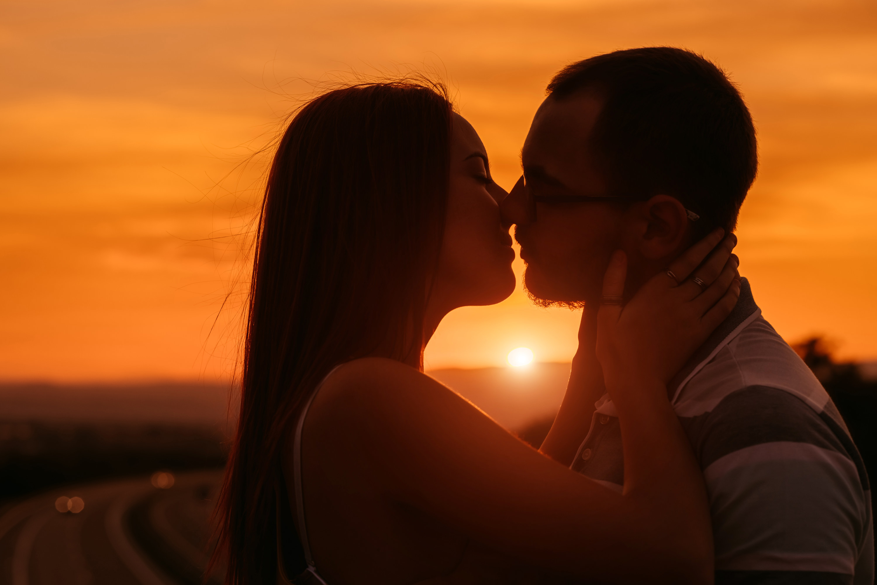 Two people kissing with the setting sun behind them