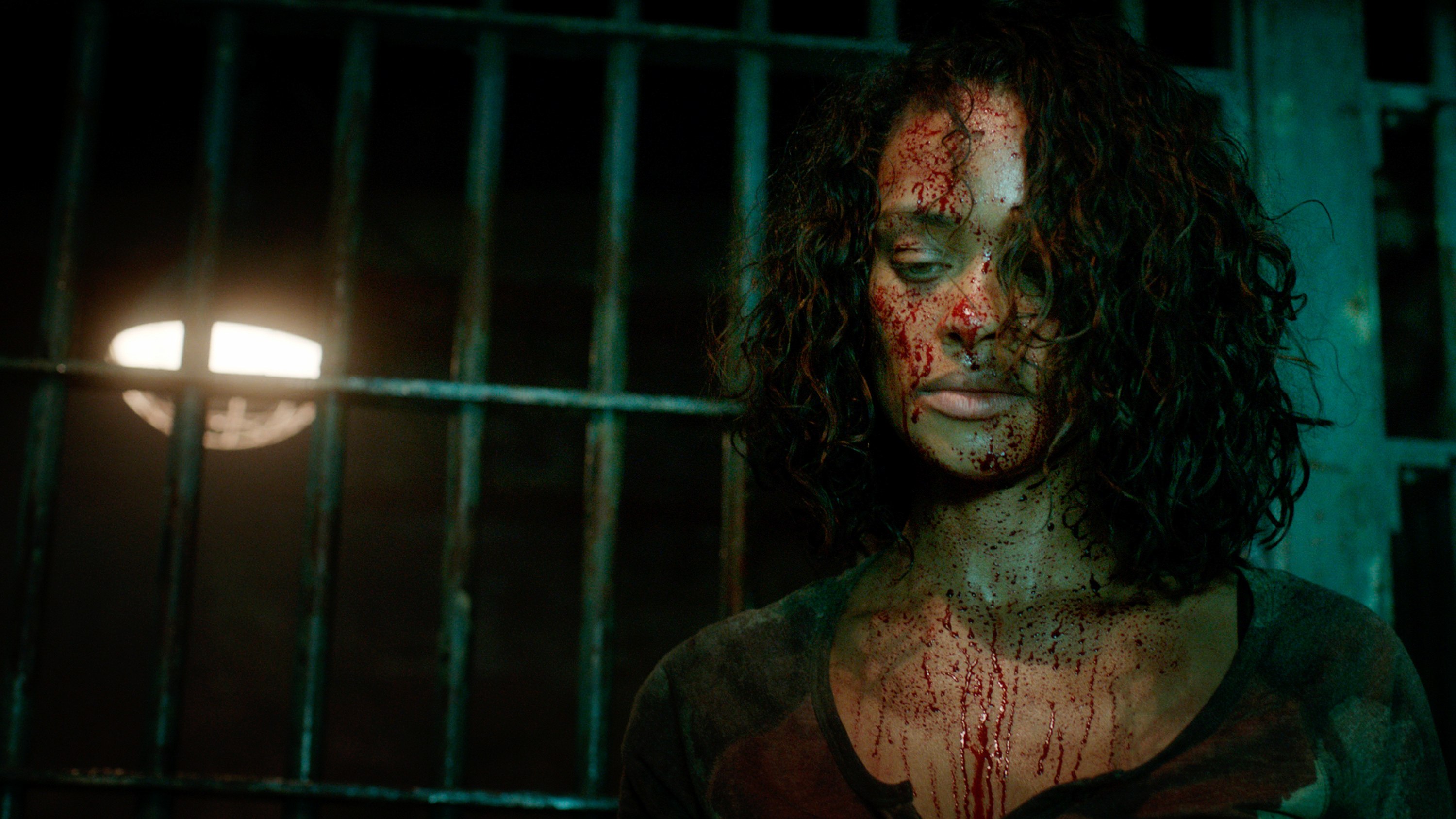 A woman, bloodied, looks down at something off screen
