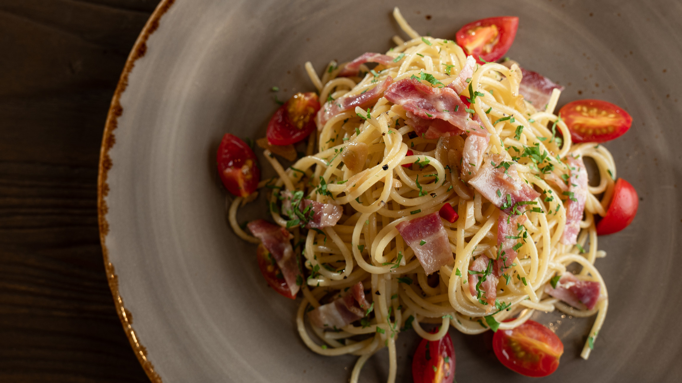 A plate of pasta with tomatoes and bacon.