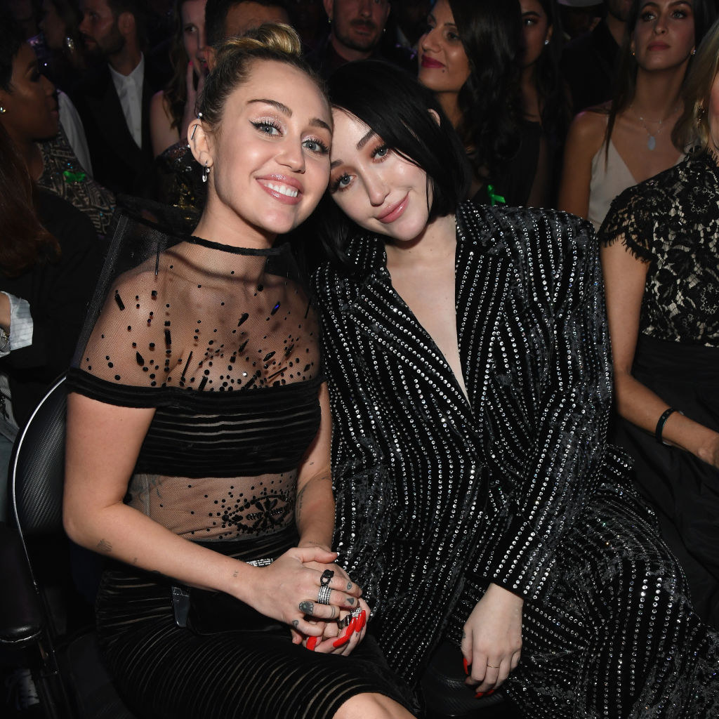 Noah and Miley Cyrus sitting together and smiling