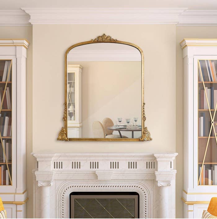 the large gold mirror hung over a fireplace