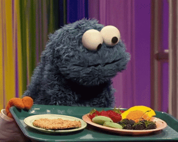 Cookie Monster looking at two plates.