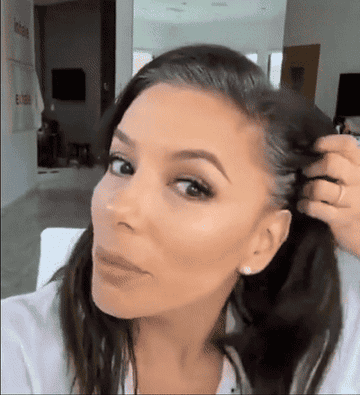 a gif of Eva Longoria using the spray to cover her roots