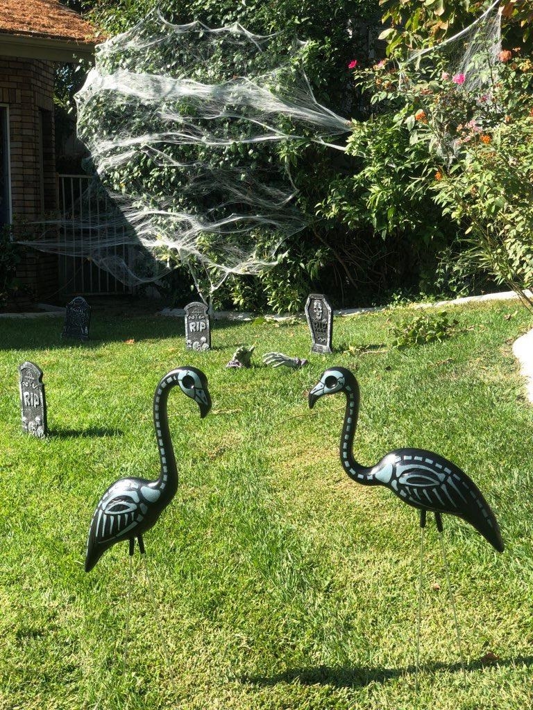 Reviewer&#x27;s two flamingos are shown on a lawn with other Halloween decorations