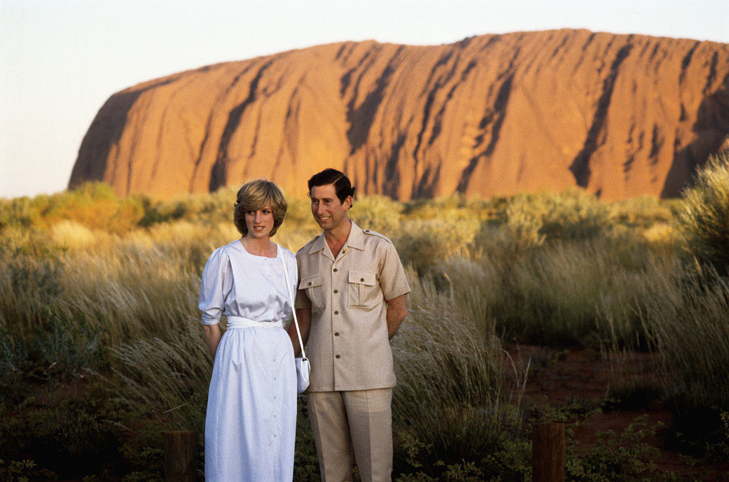 the Prince and Princess standing by Uluru in white and khaki vacation clothing