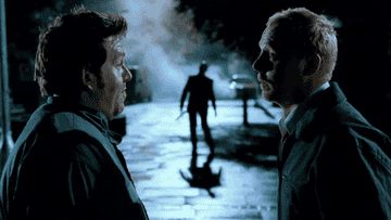 Two men look at each other and then at the zombie in the background