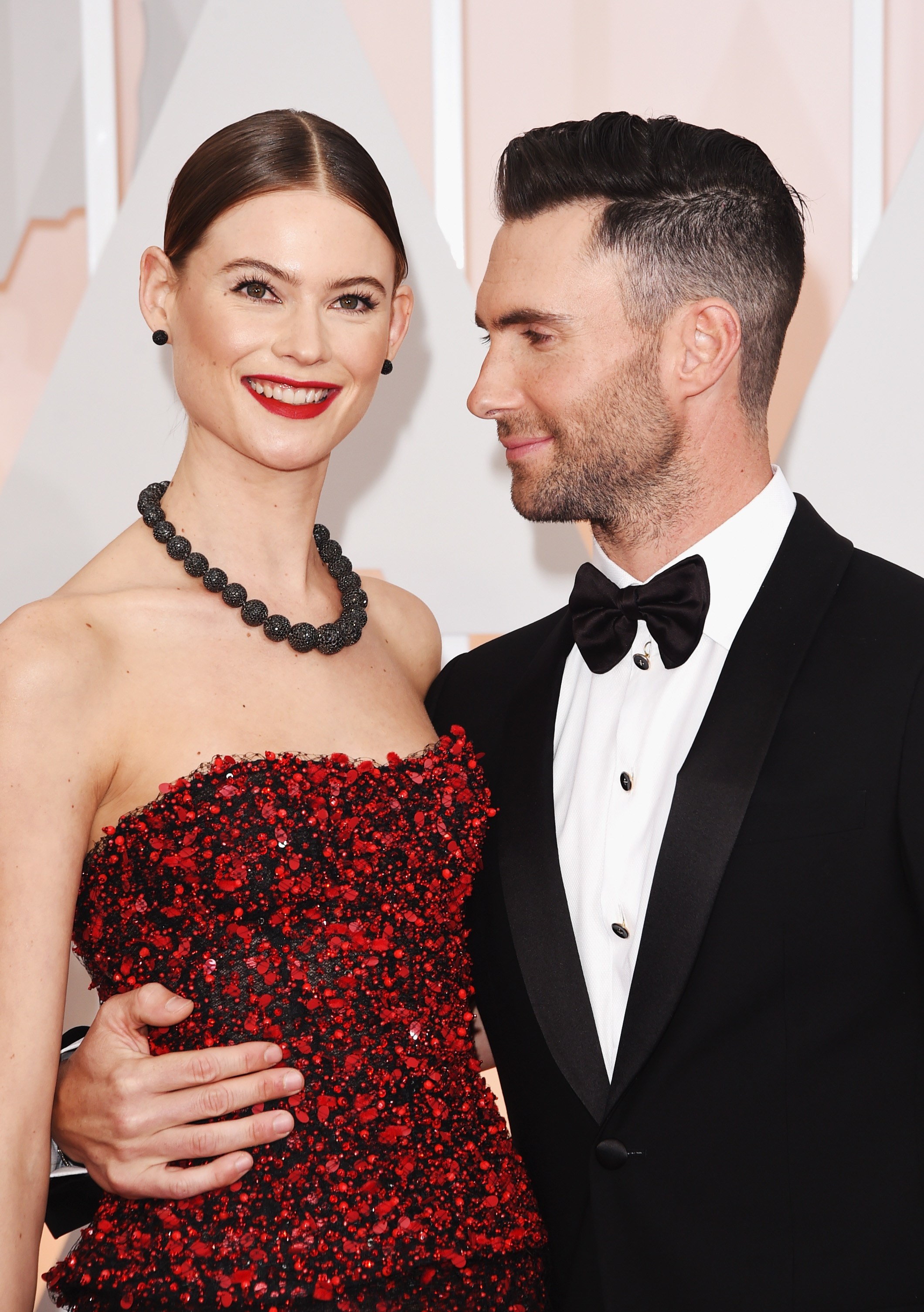 Adam smiling at Behati and wearing a bow tie
