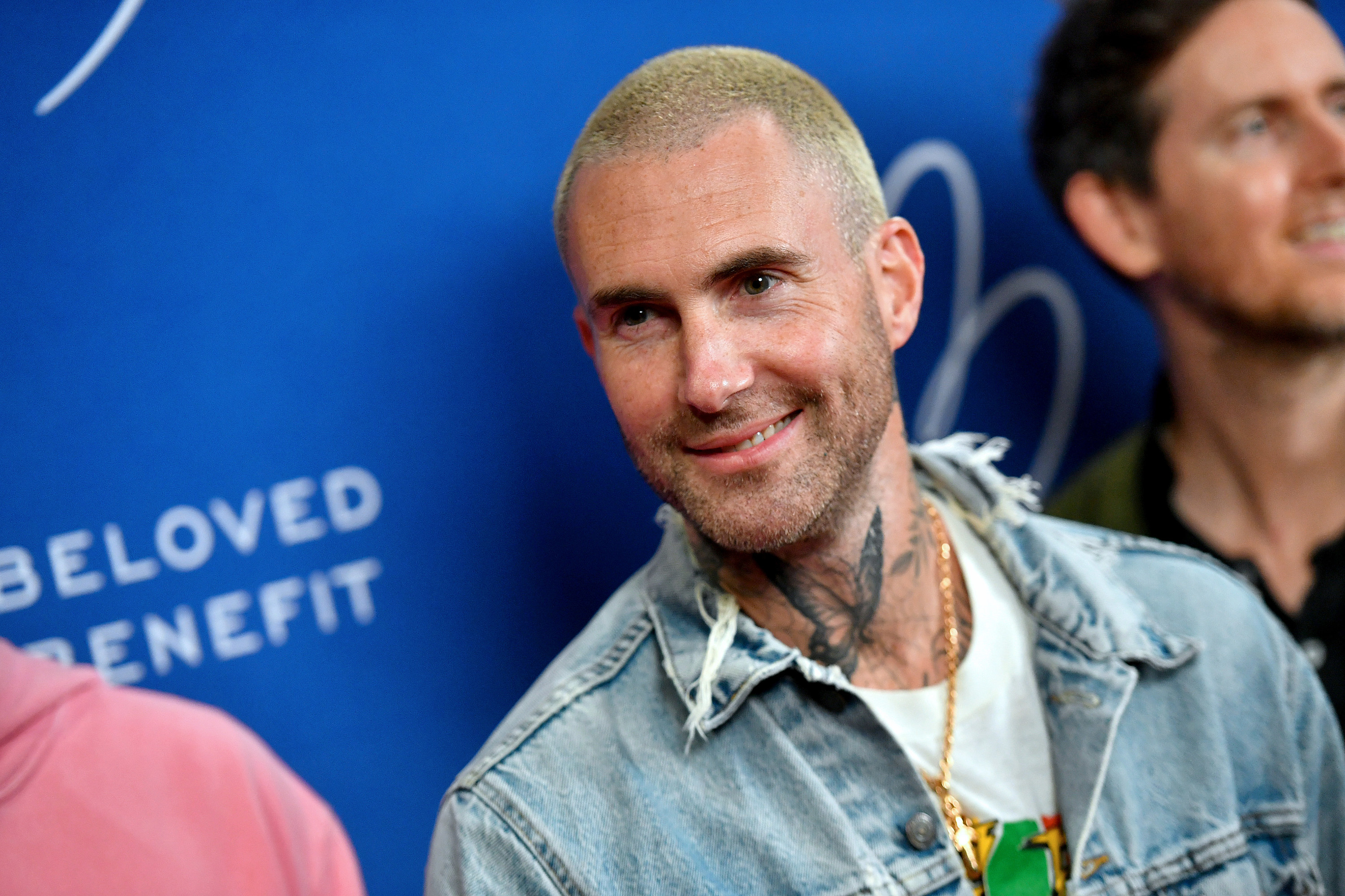 A smiling Adam with a buzz cut and wearing a denim jacket