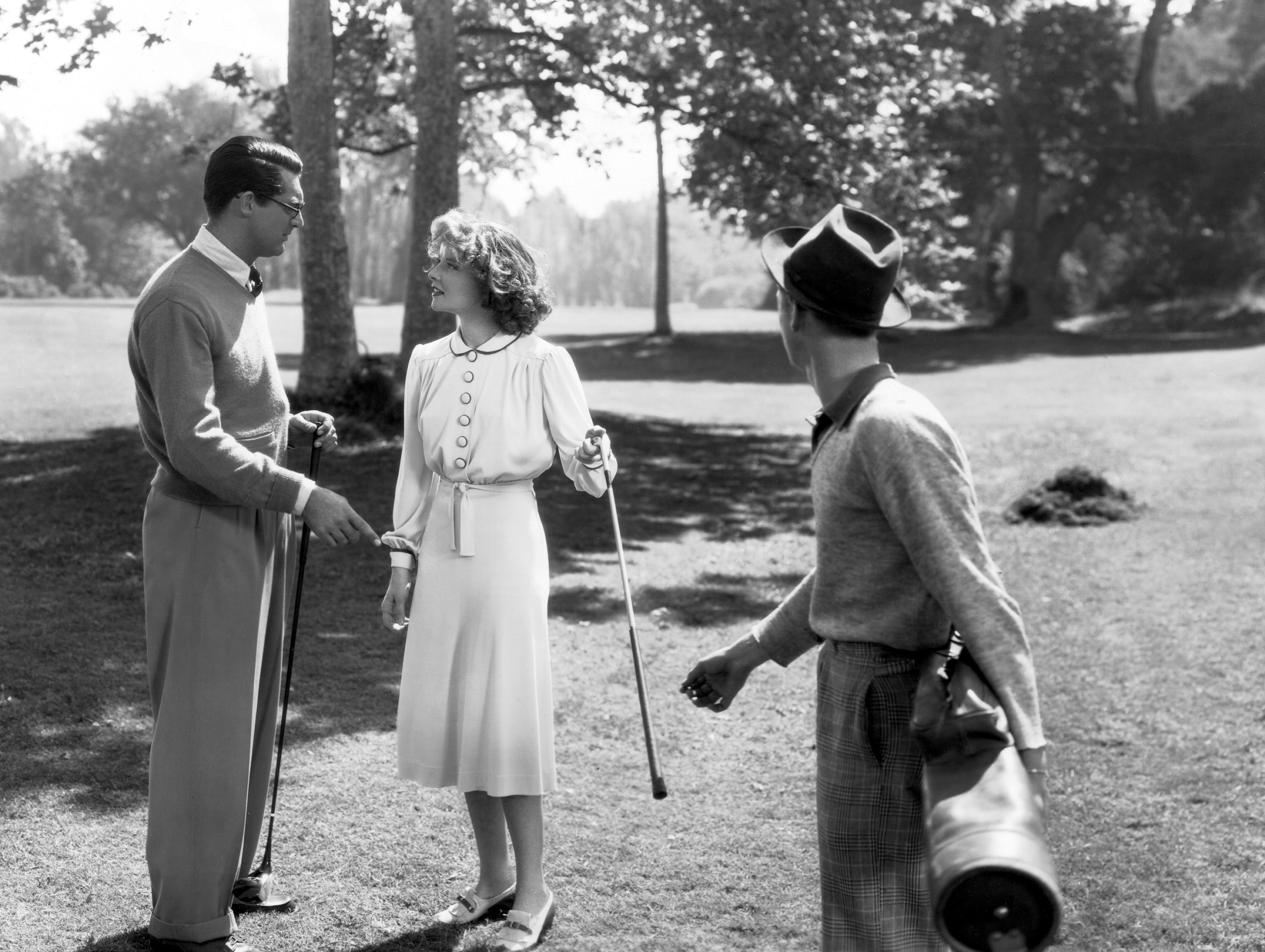 Cary Grant and Katharine Hepburn talking on a golf course.
