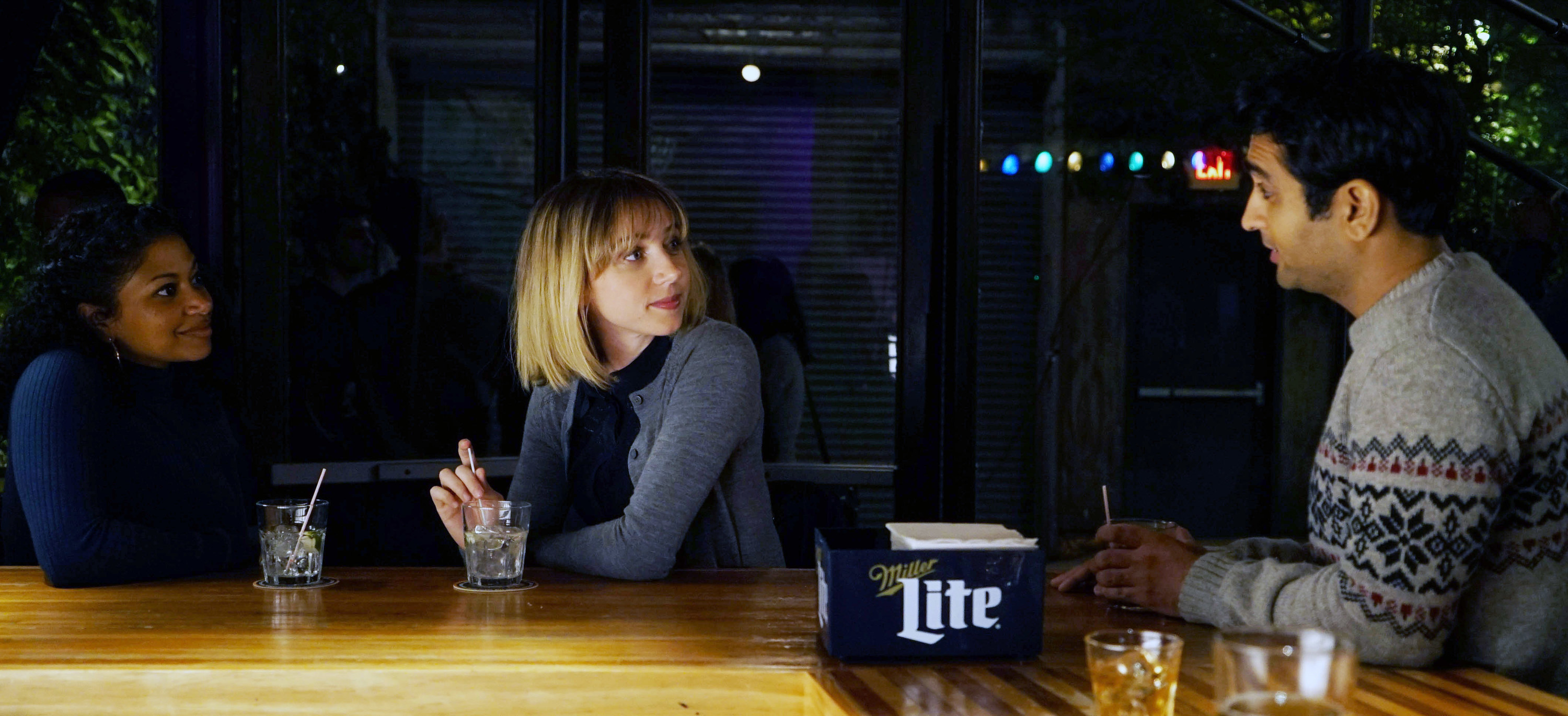 Rebecca Naomi Jones, Zoe Kazan, and Kumail Nanjiani talking at a bar.