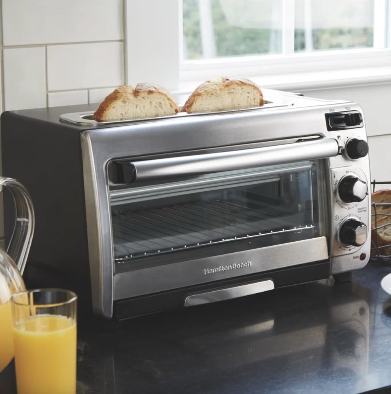 the toaster oven on a counter with two pieces of bread popping out of the slots on the top