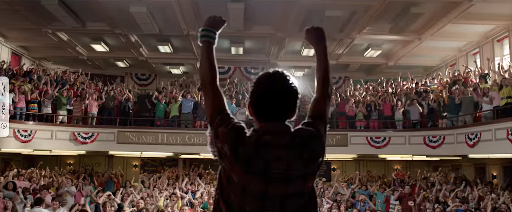 Boy raising his arms in triumph in front of a crowd