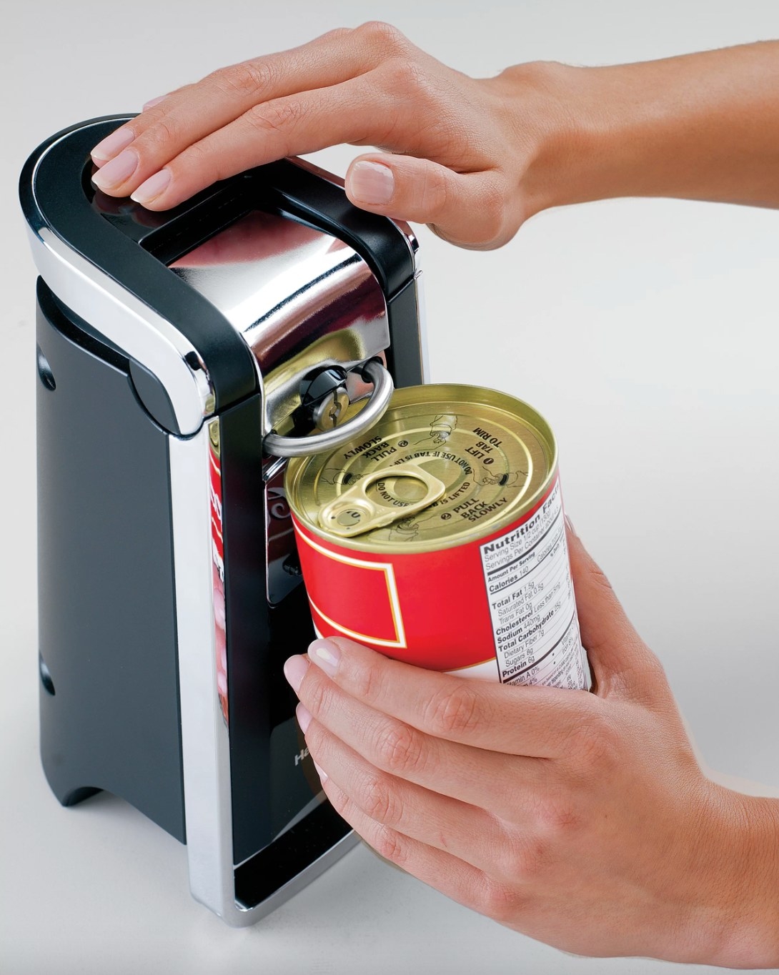 a model using the black electric can opener to open a red can