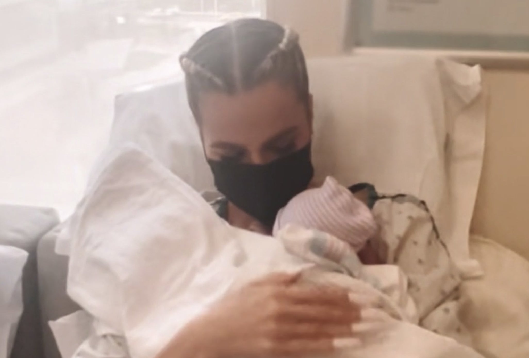 Khloe sits with a baby on her chest covered in blankets