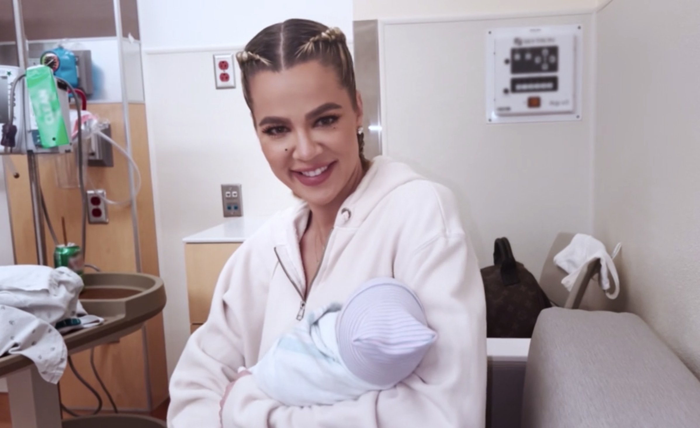 Khloe smiles while holding the baby