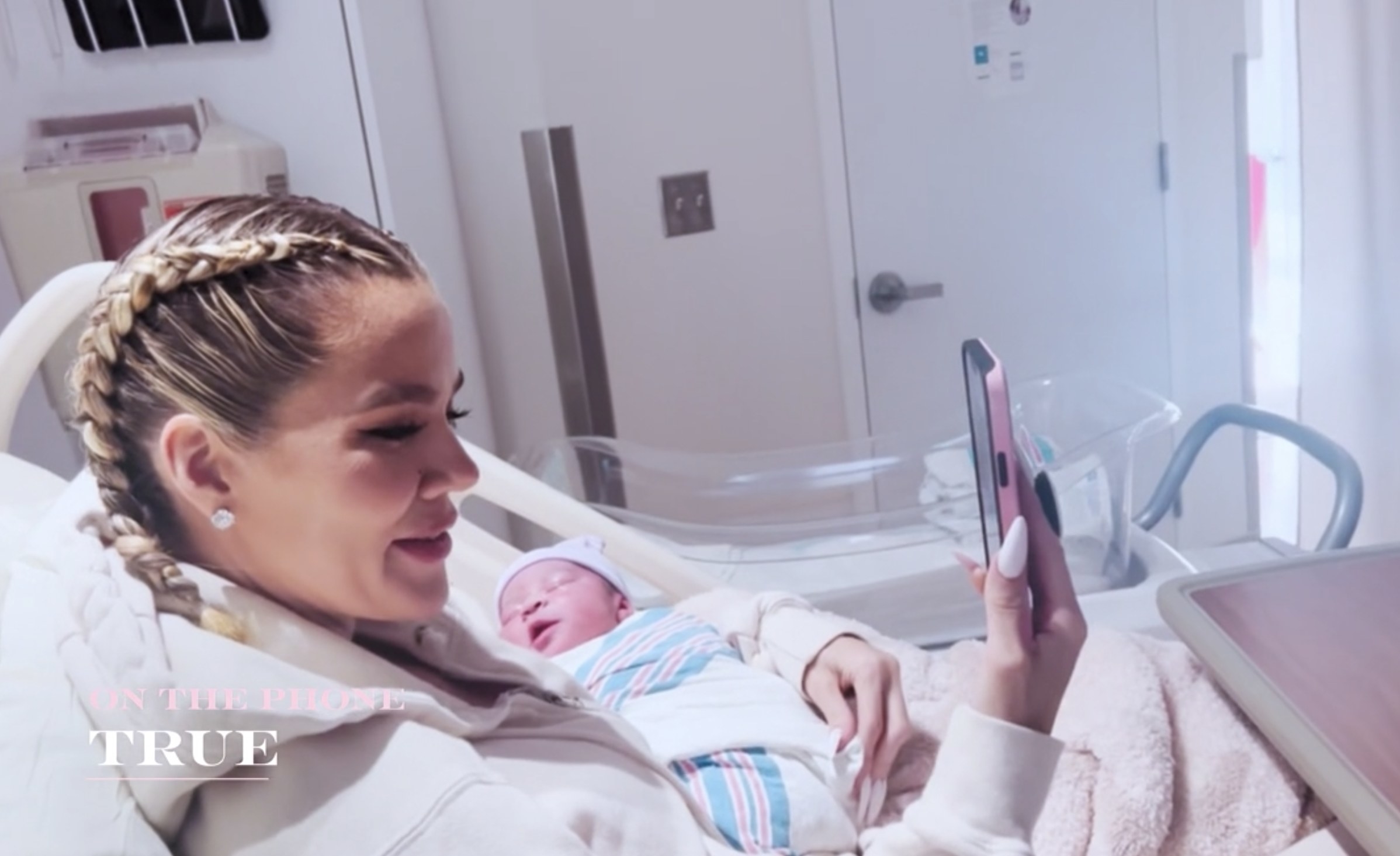 Khloe smiles while holding the baby and talking on Facetime to True