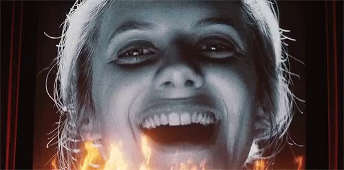 A woman on a screen laughs manically in flames