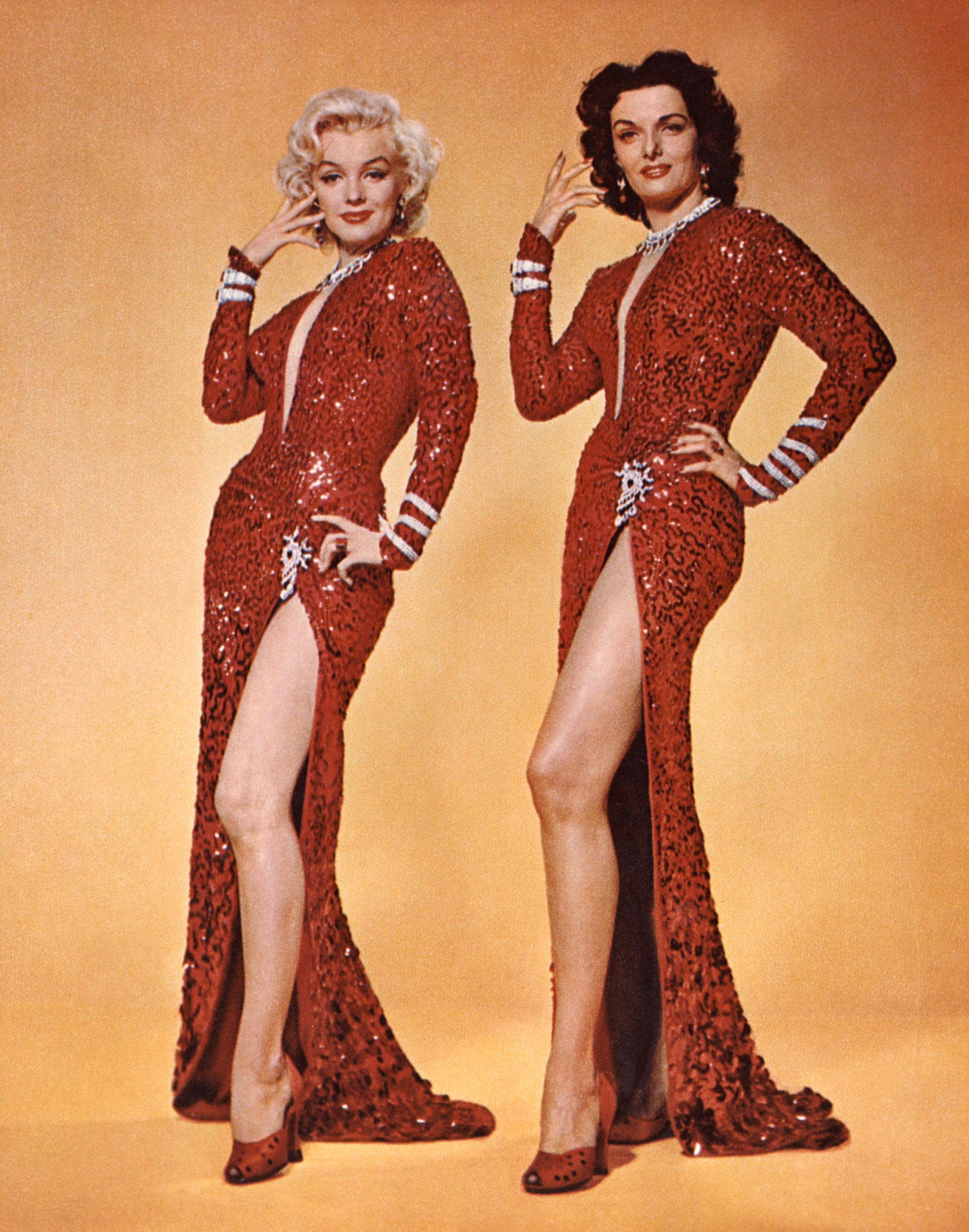Two women pose in red dresses