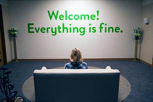 Eleanor Shellstrop sits in front of a sign saying "Everything is Fine"