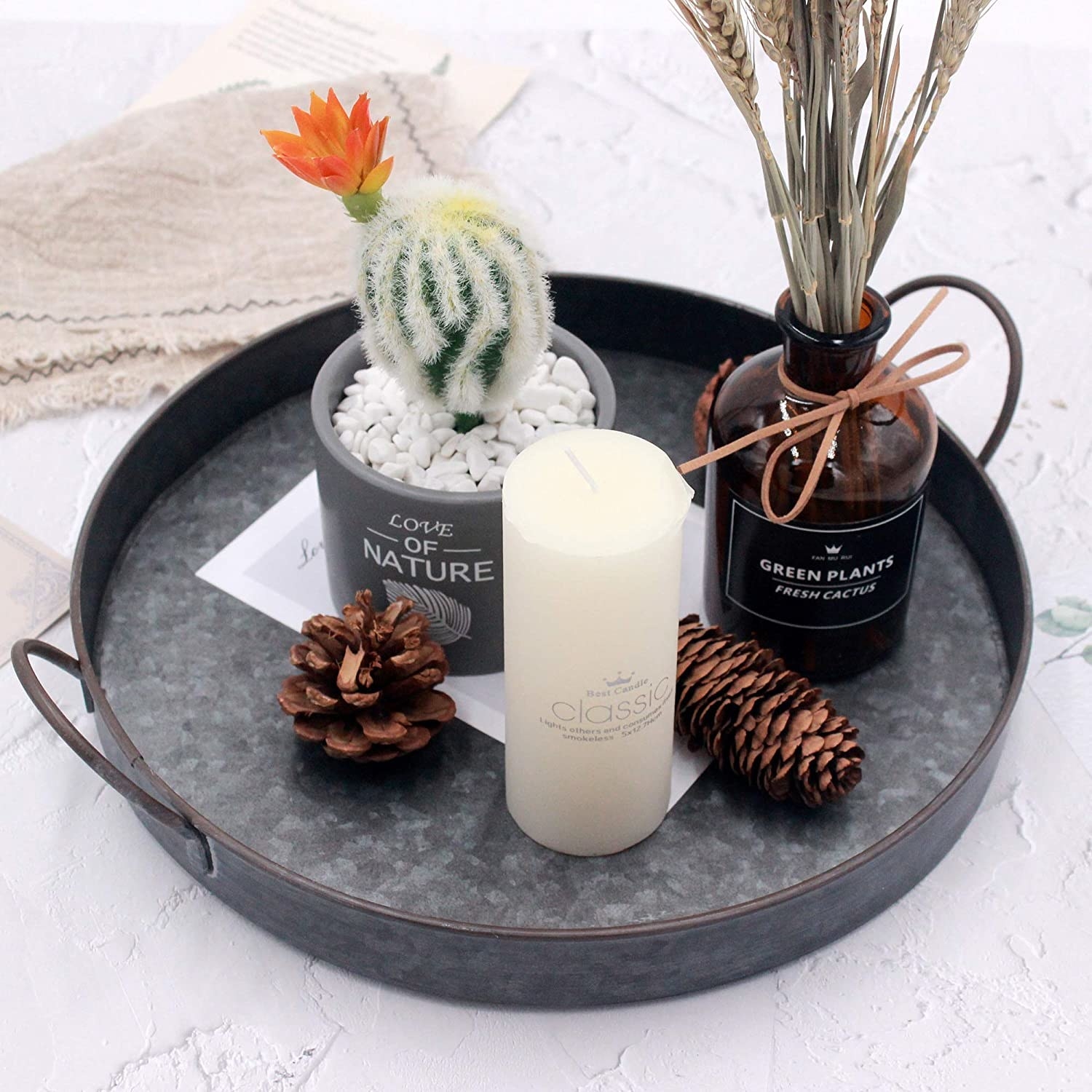 the tray with pines cones, a candle and a daux cactus in it