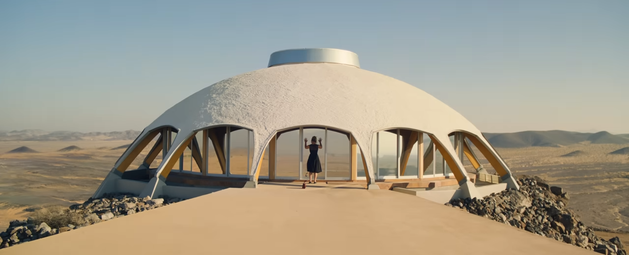 A person standing in front of a domed structure with windows on all sides