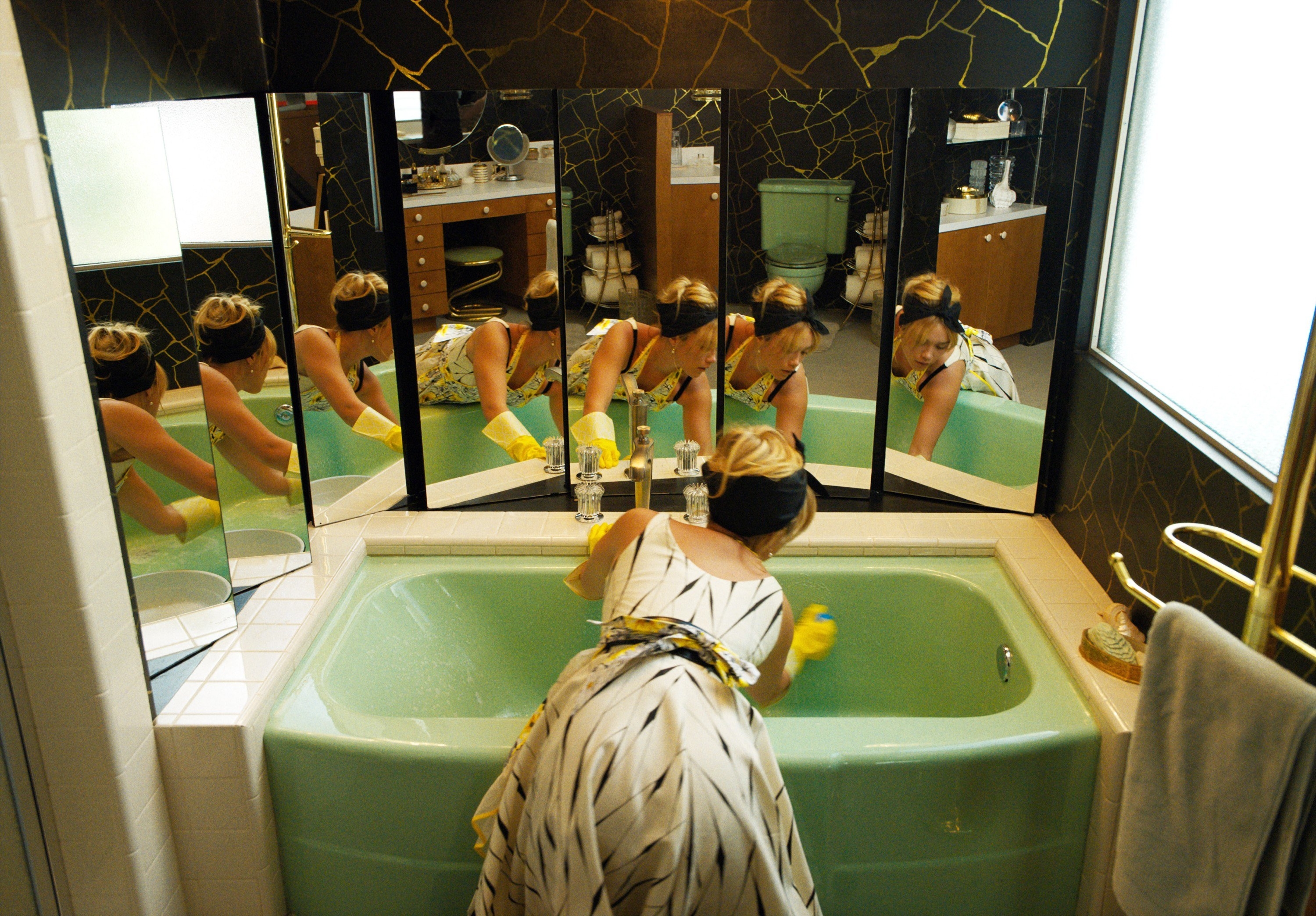 Alice scrubbing a bathtub that has several mirrors behind it
