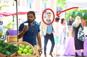 Donald Glover on set shooting a scene with an extra walking through the background and there's a red circle around the extra's face