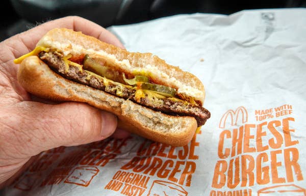 A man holding a McDonald's cheeseburger.