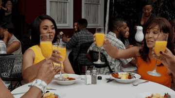 Women toasting with mimosas around a table