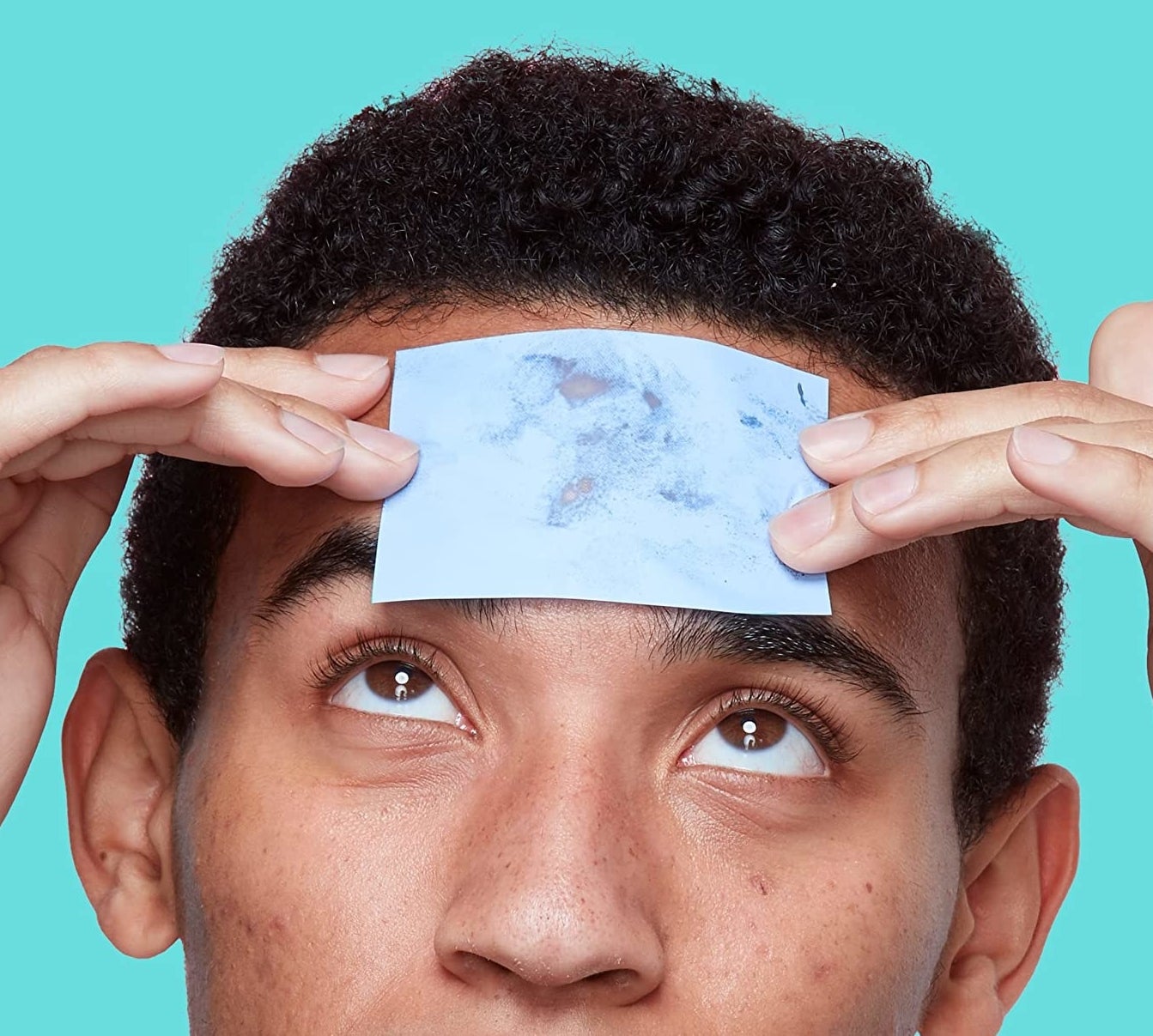 A person using a paper to blot their forehead