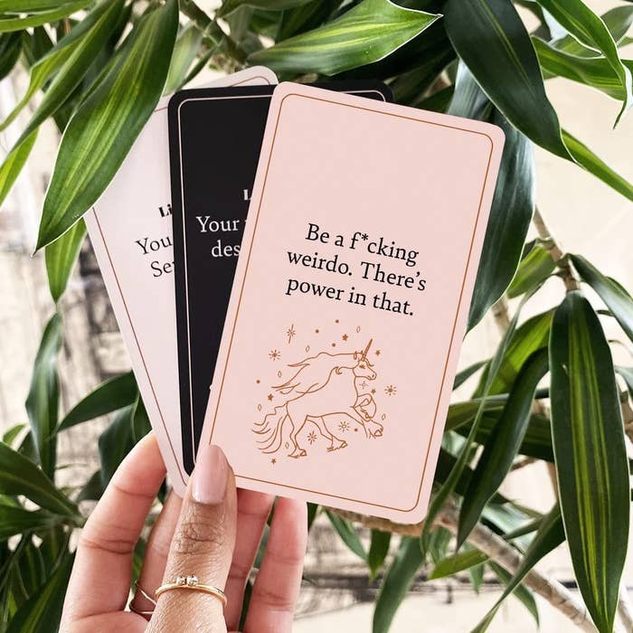 a person holding a few of the cards in front of a plant