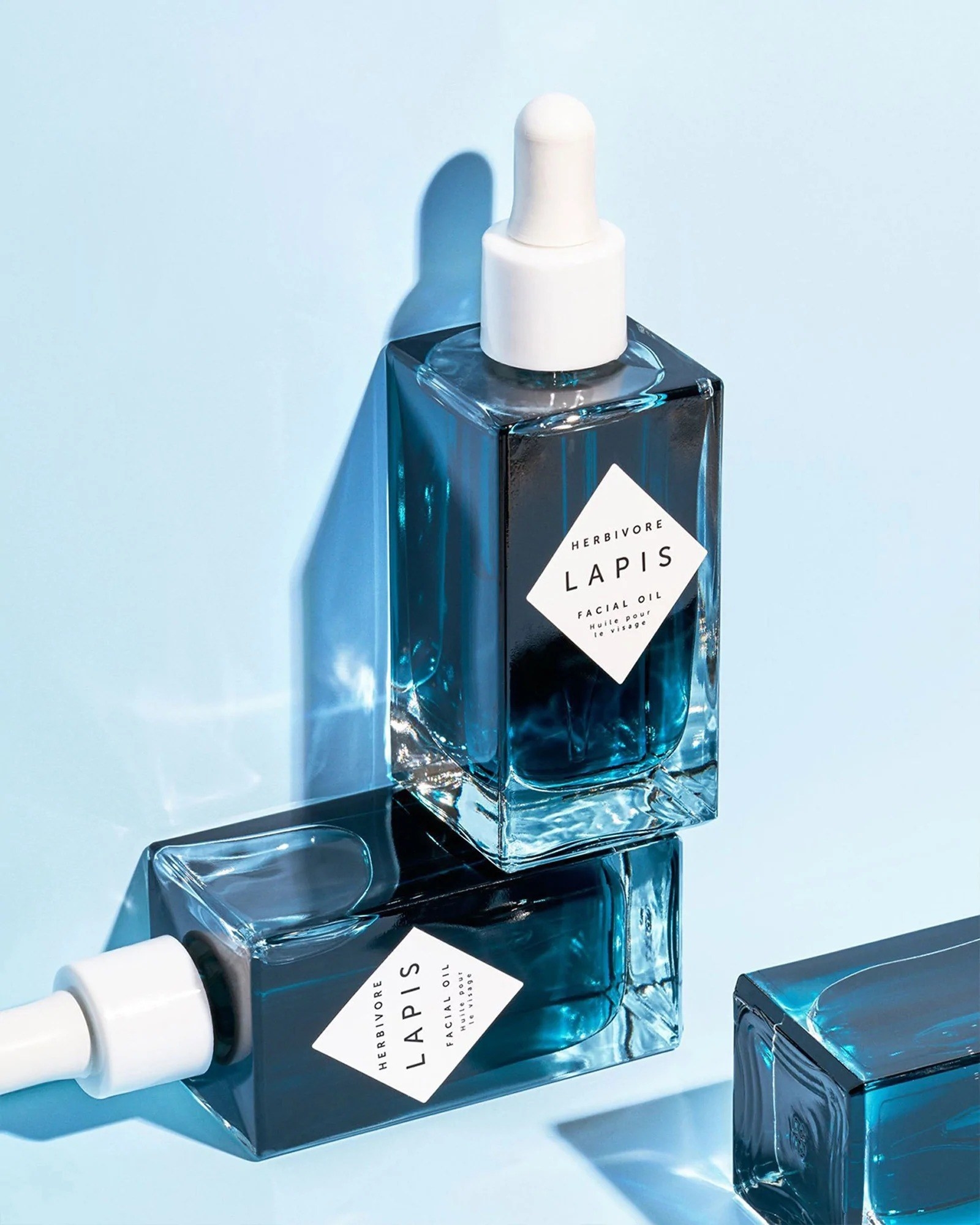 bottles of the Lapis facial oil filled with dark blue skincare formula