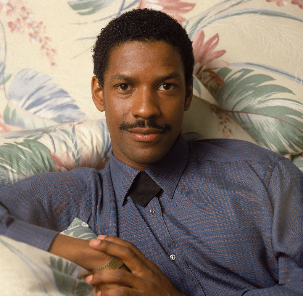 Denzel smiling and sitting on a couch