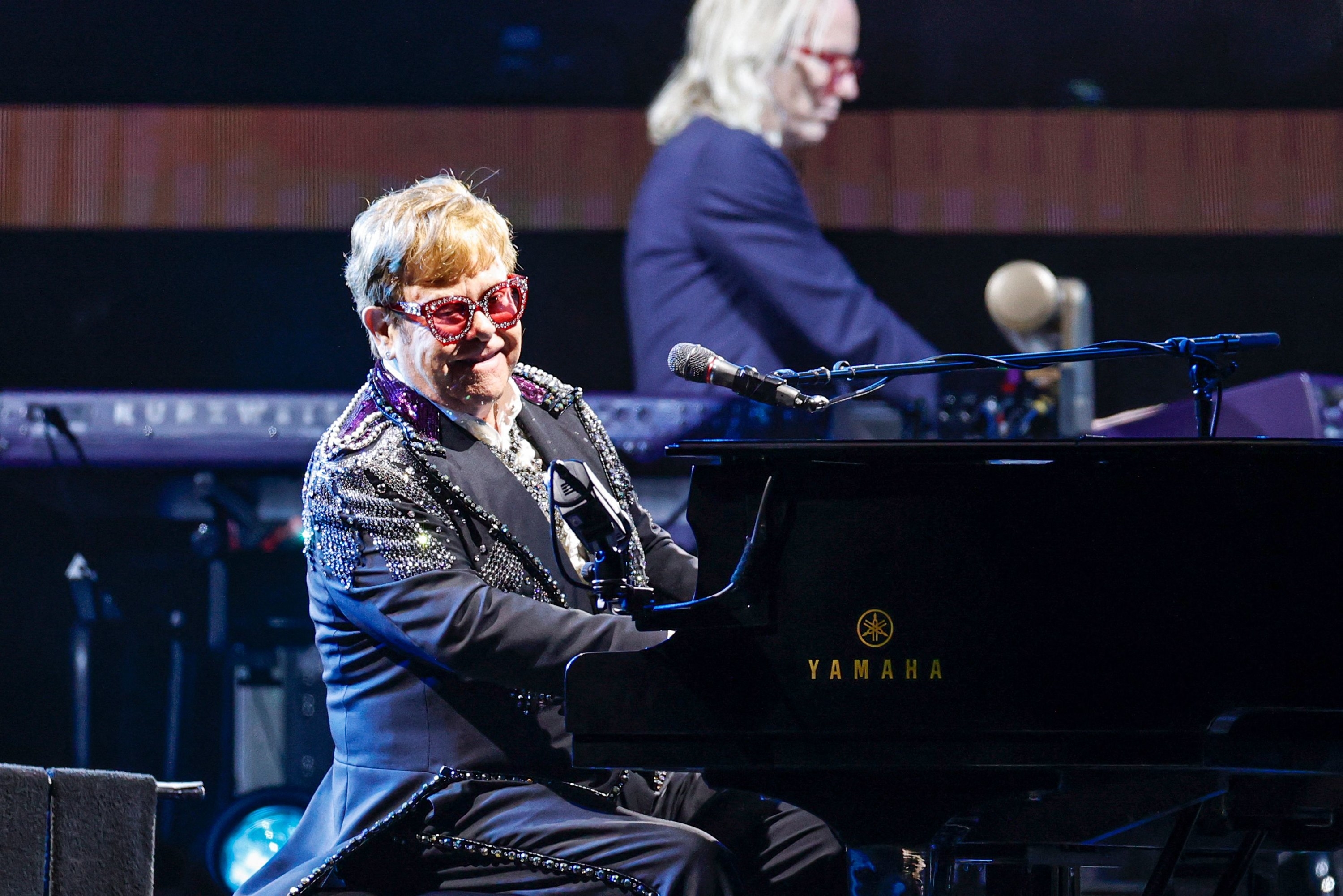 Elton John smiling and performing at the piano
