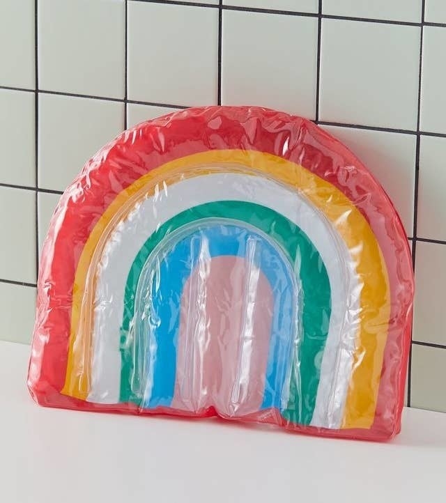 a rainbow bath pillow on a tub