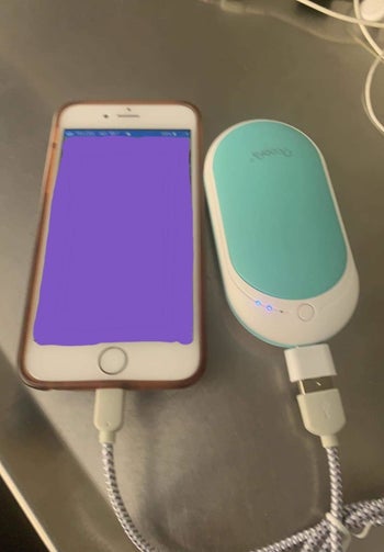 reviewer using the warmer to charge their phone