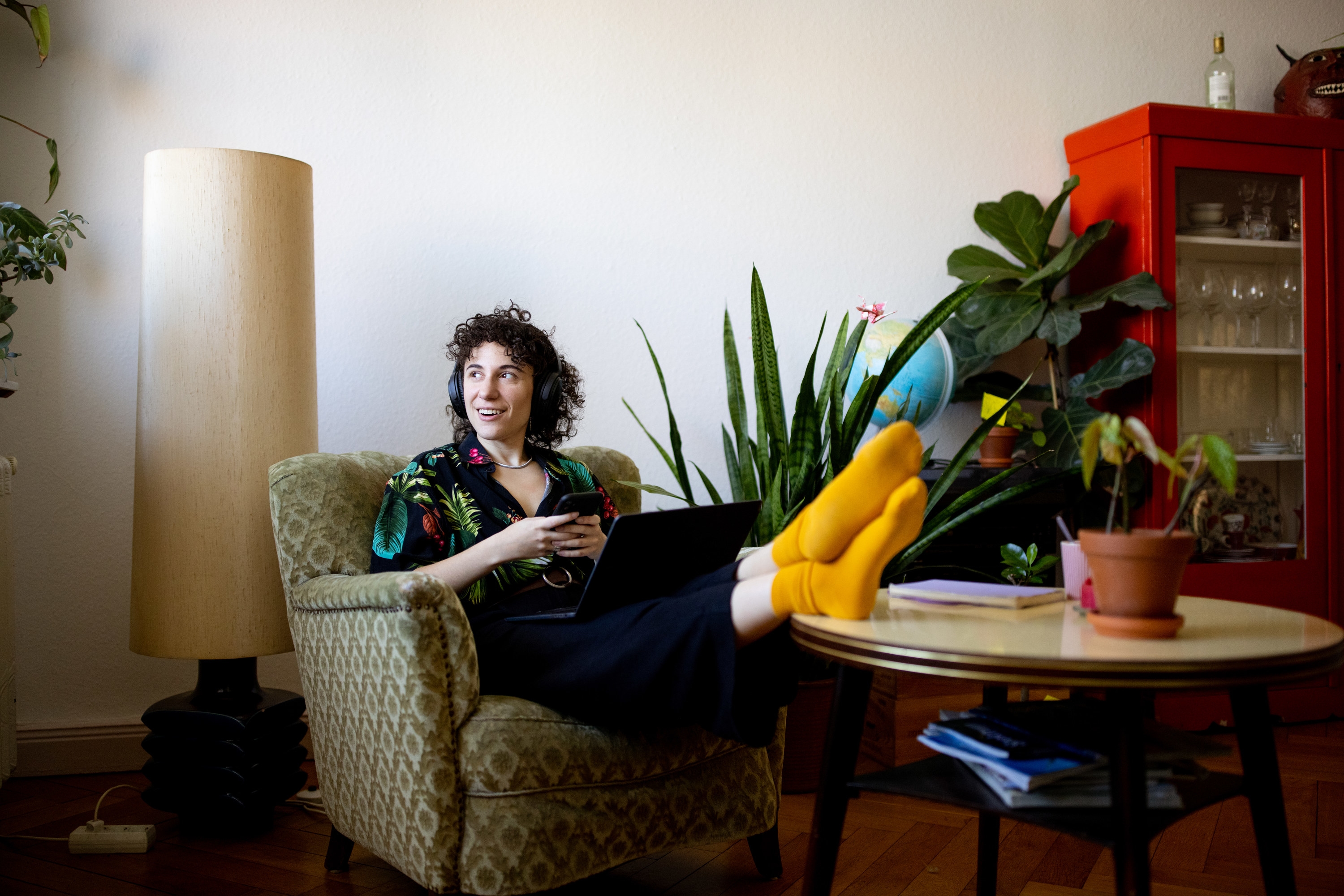 person sitting in armchair in home listening to music and looking relaxed