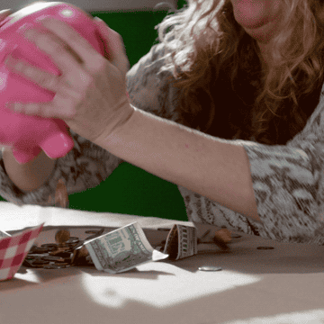 woman shaking piggy bank to find coins and dollars