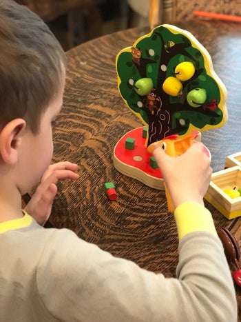 reviewer's child playing with the apple tree toy