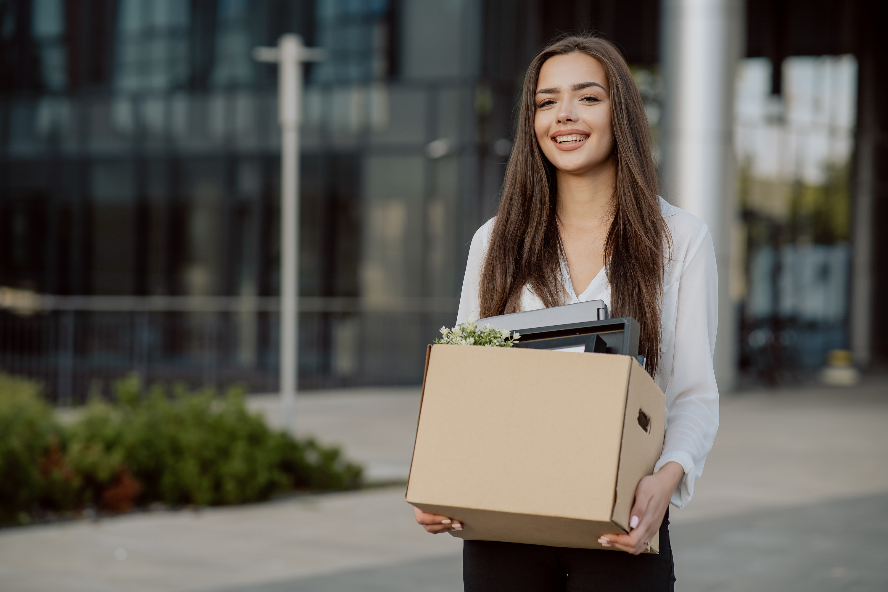 a woman holding a box of things outside and smiling