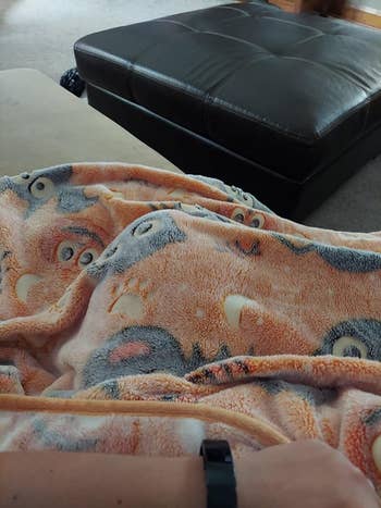 reviewer's photo of the orange blanket on the couch