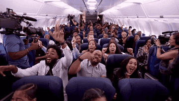 People sitting on a plane cheering and dancing