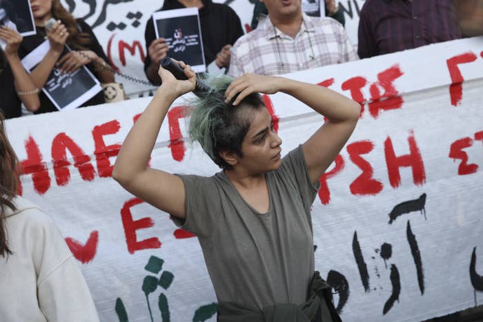 A woman shaves her head in protest