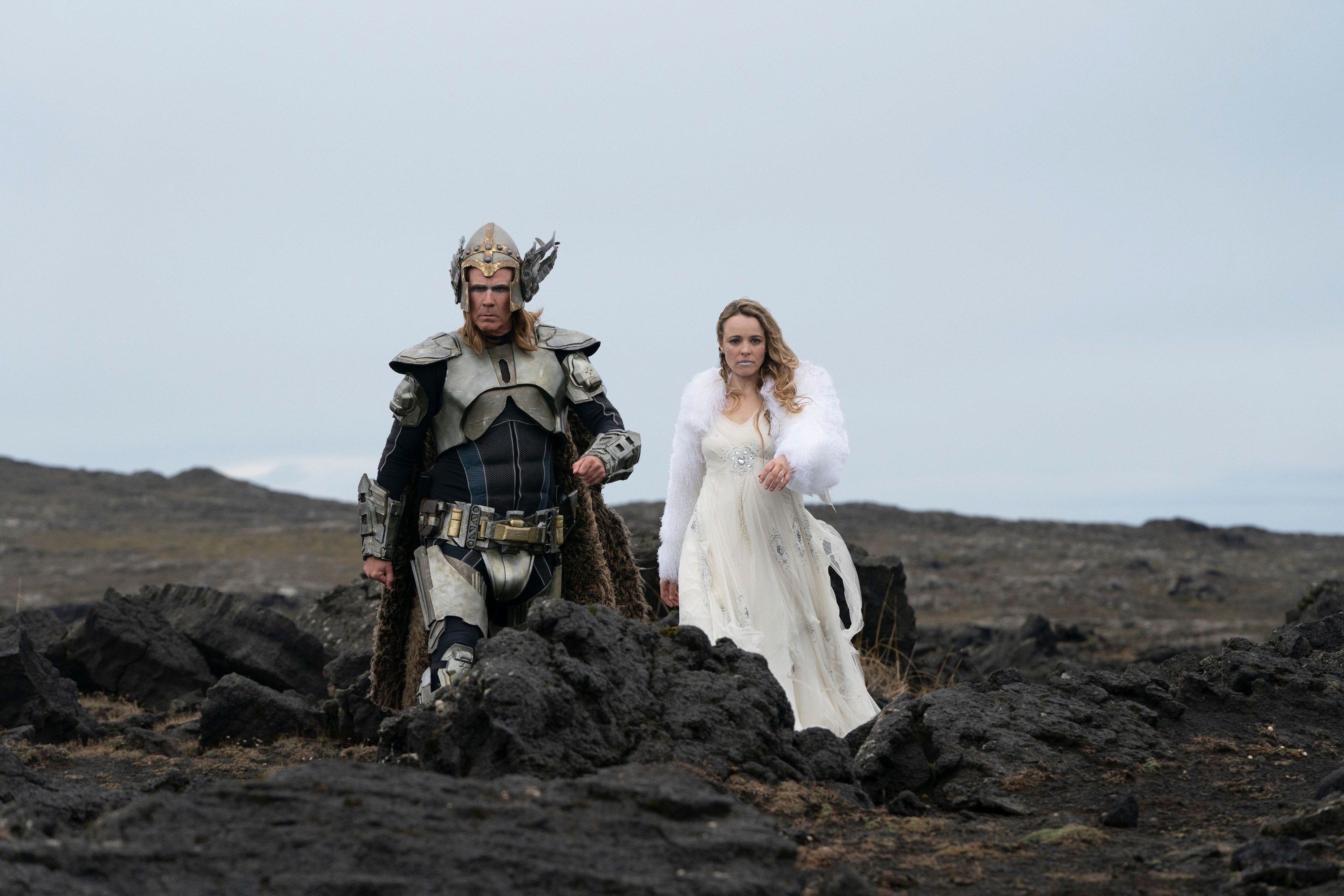 A man and a woman in viking garb walk through rocky terrain