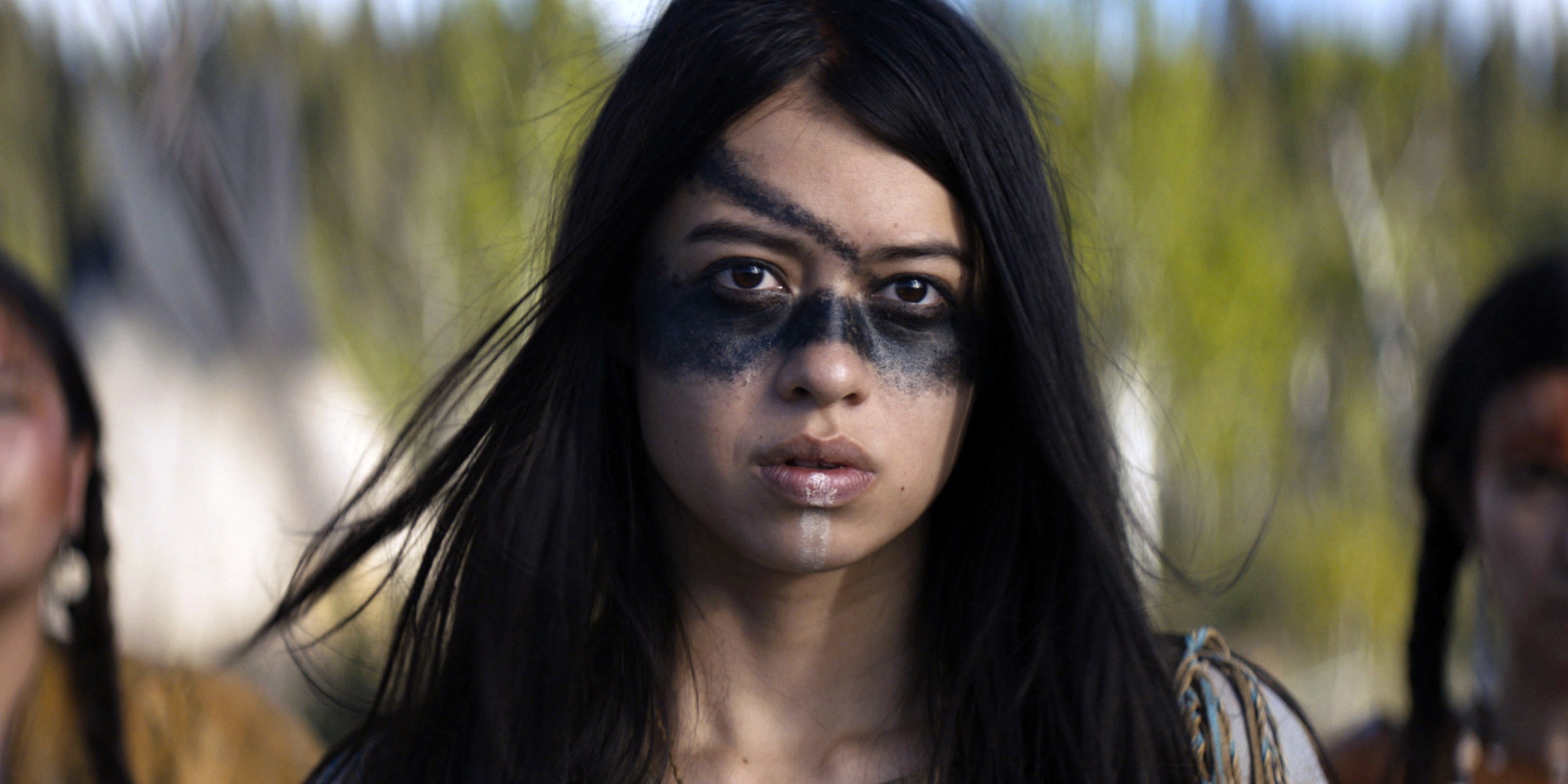 A woman in face paint stares off into the distance