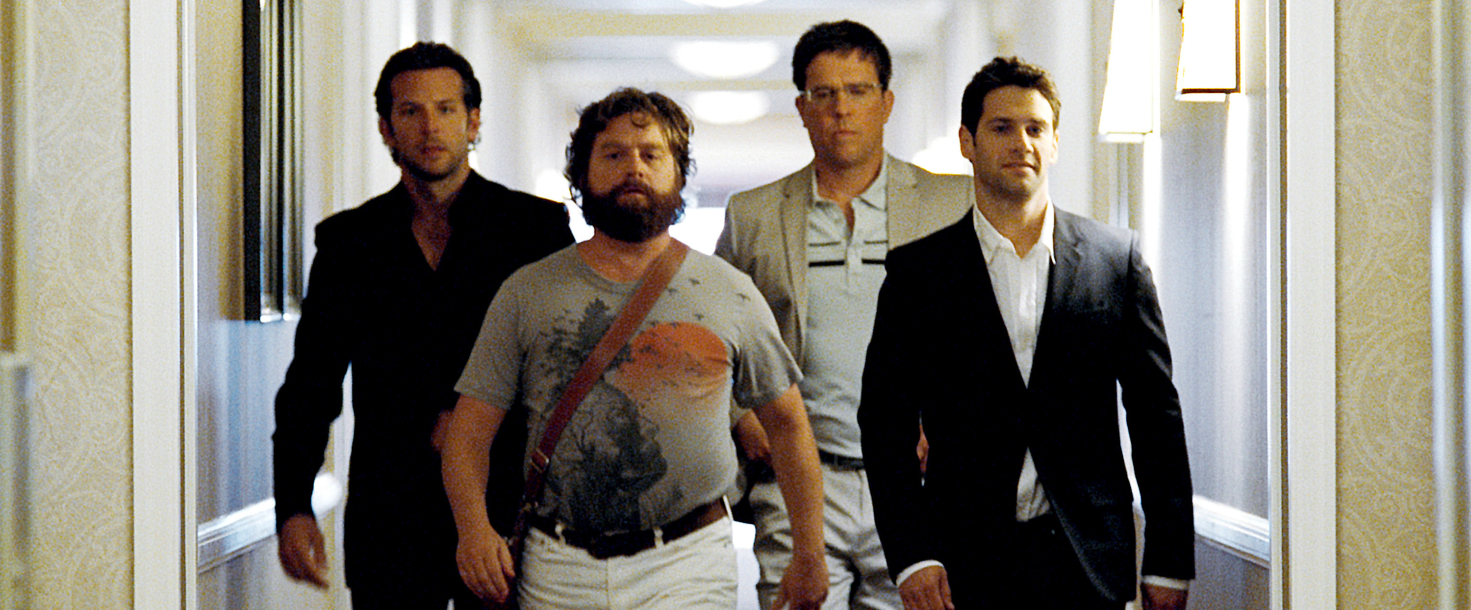 A group of four men walk down a hallway