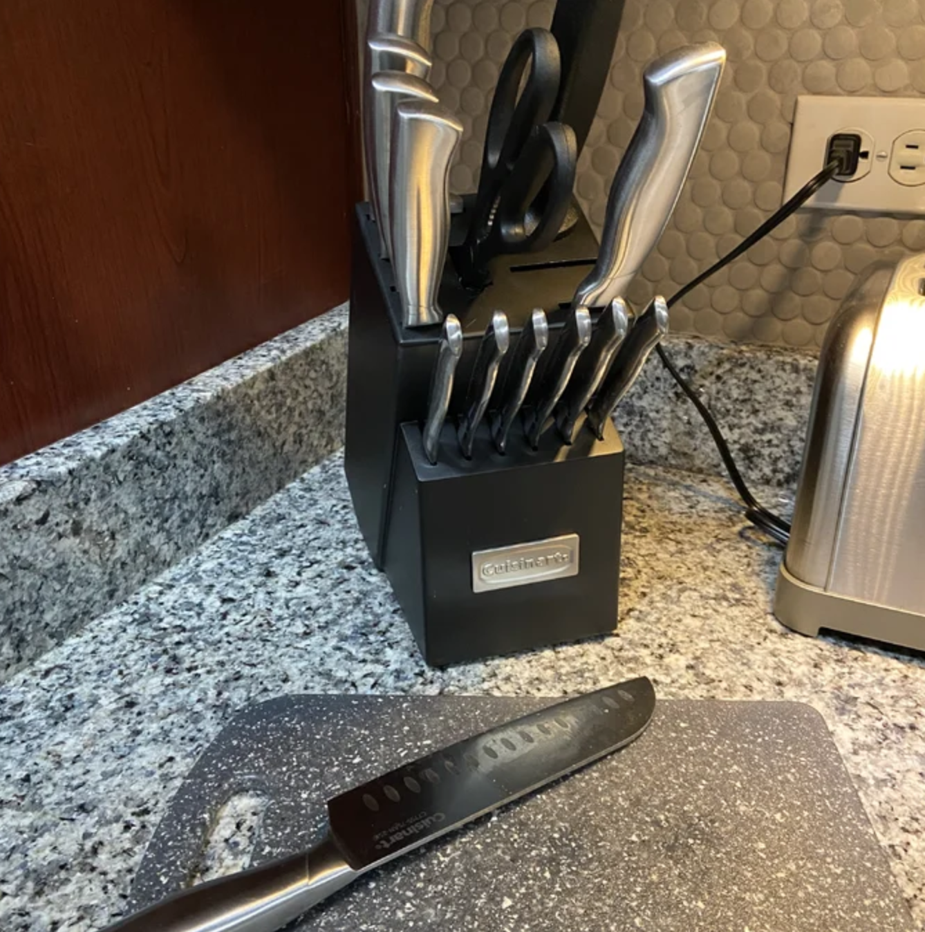 the full knife set in the black block with a knife on a cutting board in front of it
